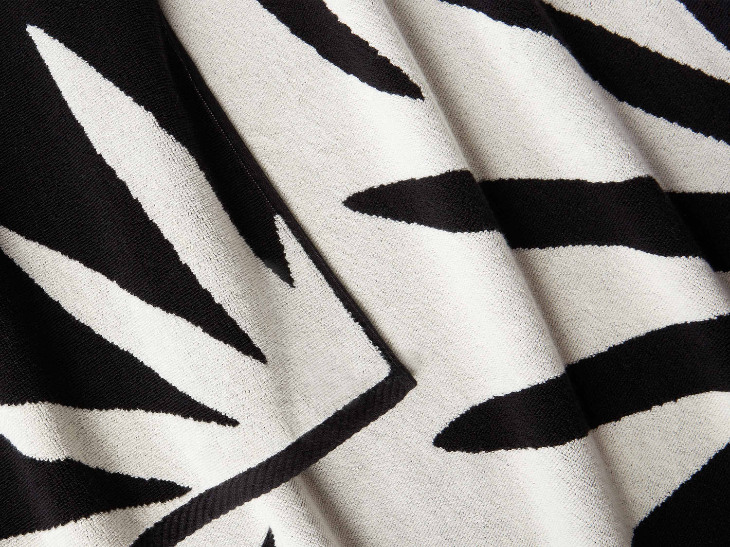 A close-up of a thick and soft, black and white tropical patterned cabana beach towel.