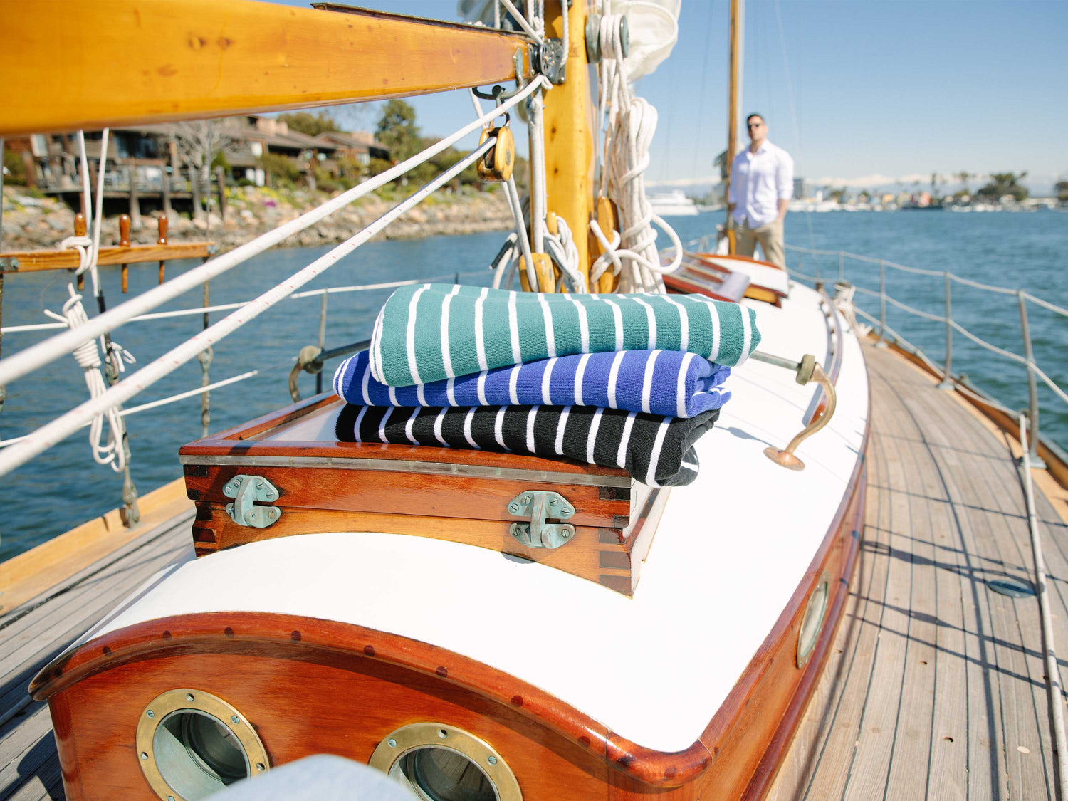 
      A stack of folded, green and white, blue and white, and black and white striped cabana beach towels on a sailboat. 
    