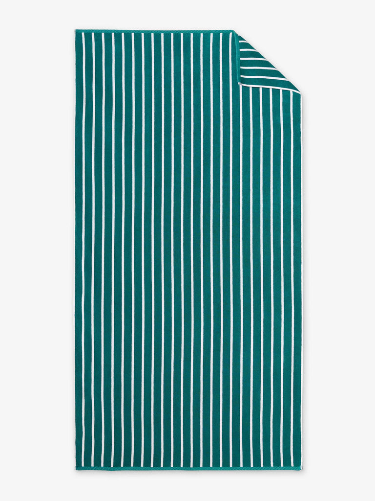 An oversized, green and white striped cabana beach towel laid out.
