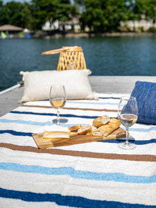 A photo of a white ivory and blue Mexican Blanket with a charcuterie board and wine on top of it.