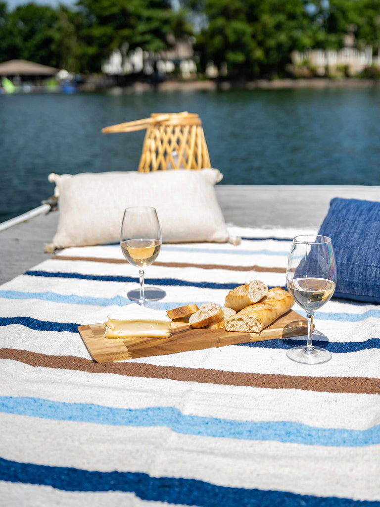 A photo of a white ivory and blue Mexican Blanket with a charcuterie board and wine on top of it.