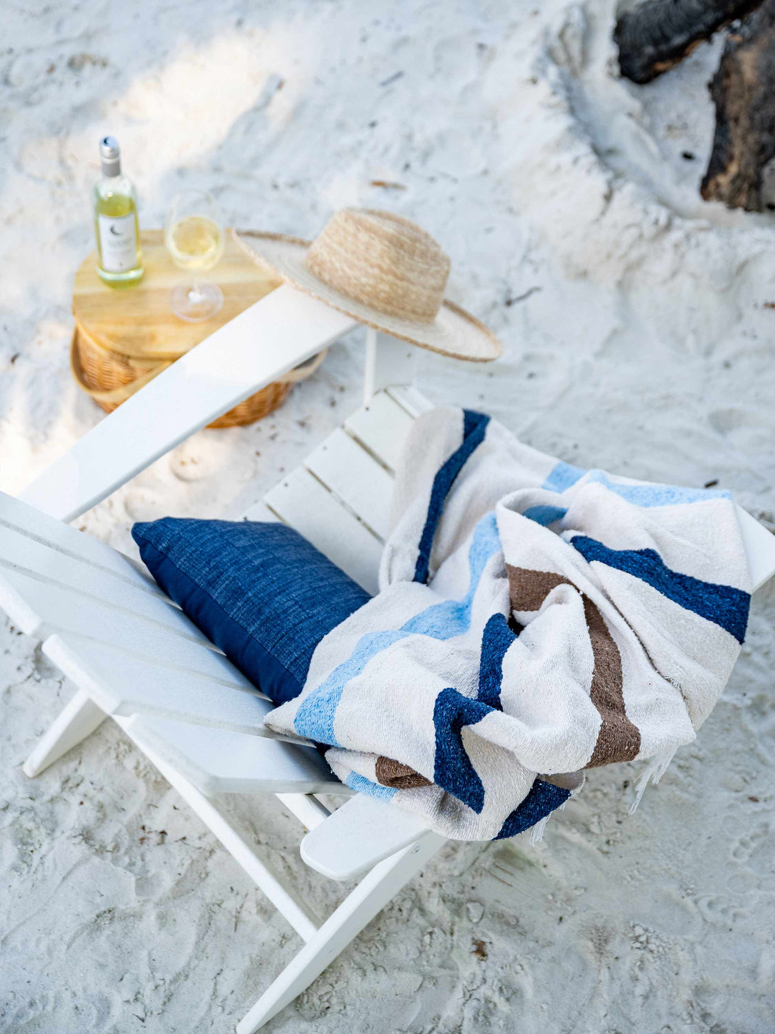 A birds eye view of a chair with a bottle of wine next to it and a Mexican Blanket draped over it.