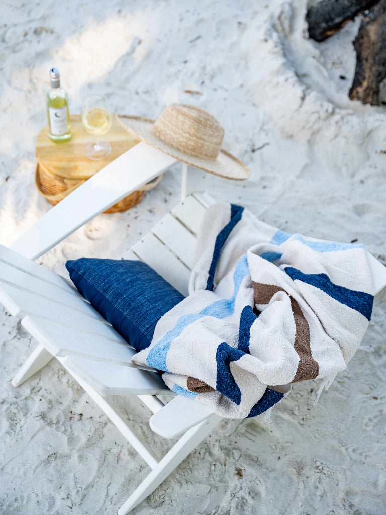 A birds eye view of a chair with a bottle of wine next to it and a Mexican Blanket draped over it.