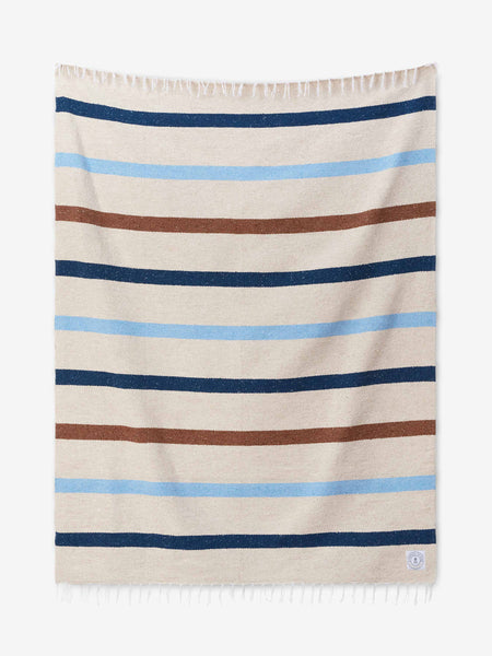A photo of a white ivory, blue, and brown striped Mexican Blanket laid out.