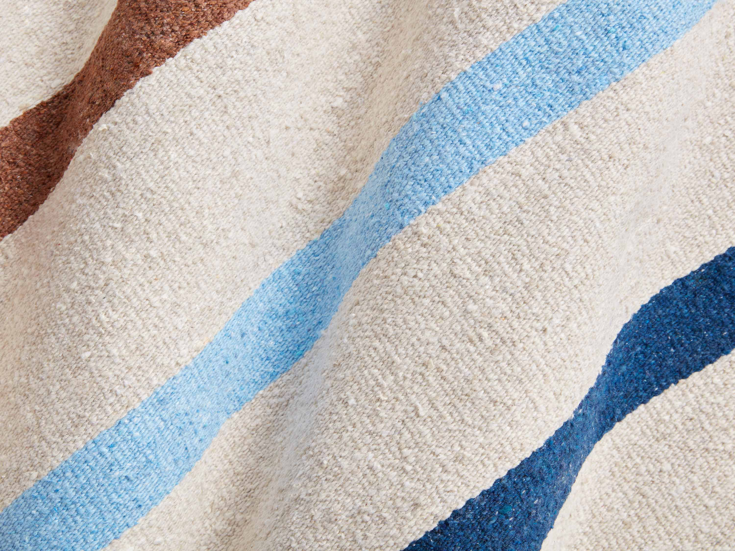 
      A detail shot of blue, and brown stripes on a white ivory Mexican Blanket.
    
