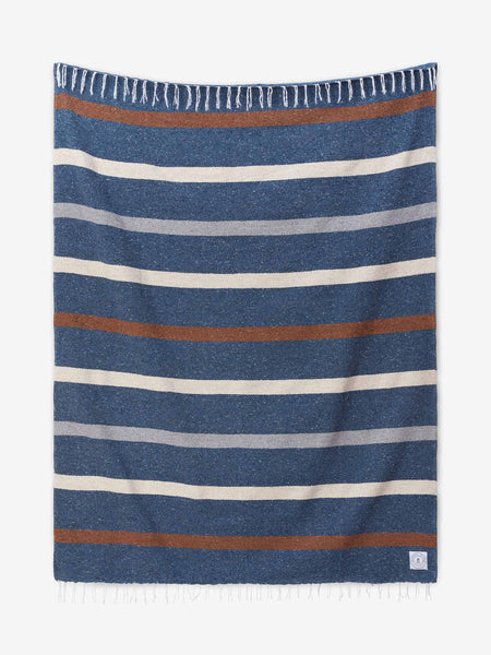 A navy, brown and white striped Mexican Blanket with tassels laid out.