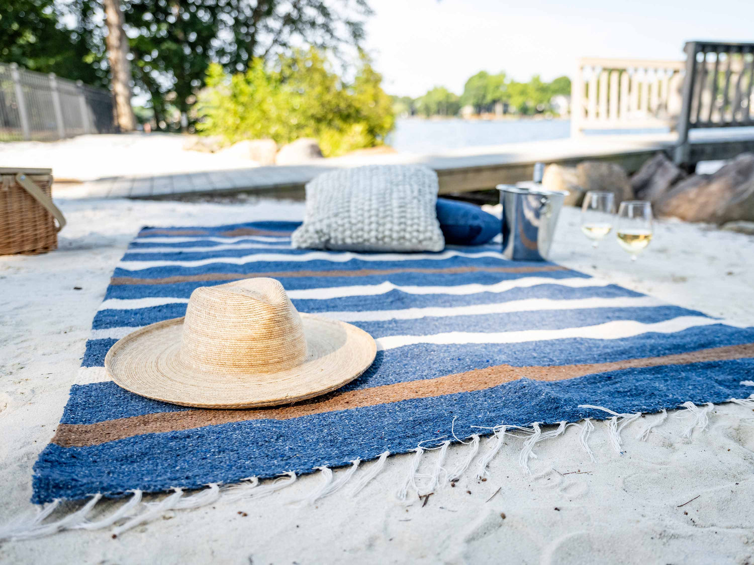 A navy, brown, and white striped Mexican Blanket laid out on the sand.