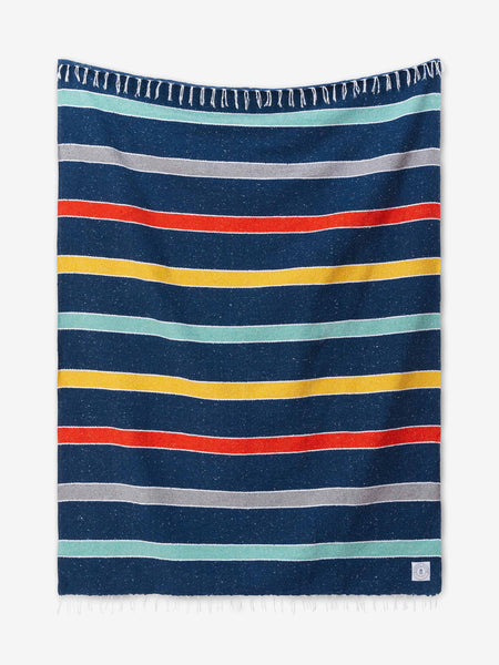 A multicolored blue, orange, and yellow striped Mexican Blanket with tassels laid out.