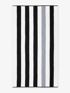 An oversized, black, gray, and white striped cabana beach towel laid out.