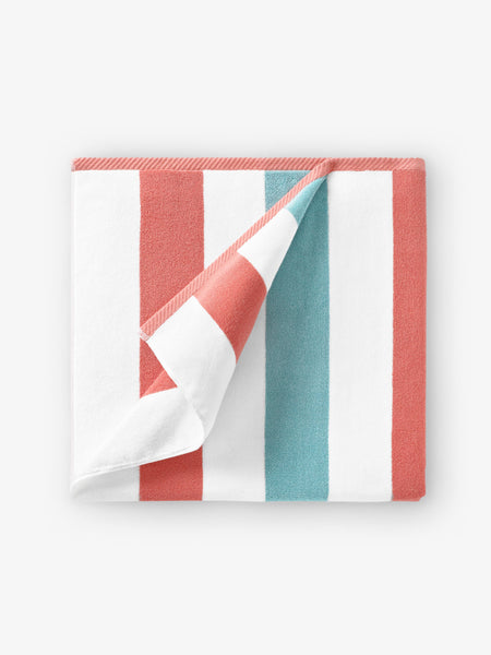 A folded orange, green, and white striped cabana beach towel.