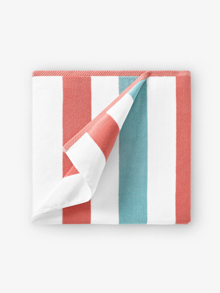 A folded orange, green, and white striped cabana beach towel.