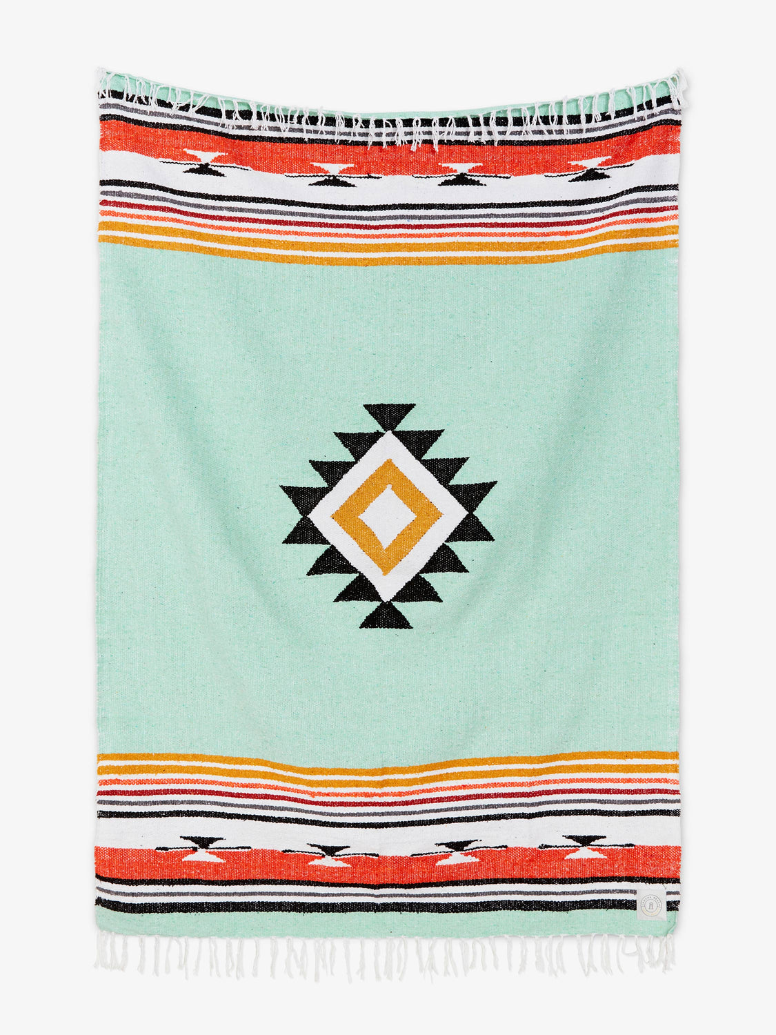 Oversized, traditional Mexican blanket in green, red, and yellow pattern with white fringe spread out.