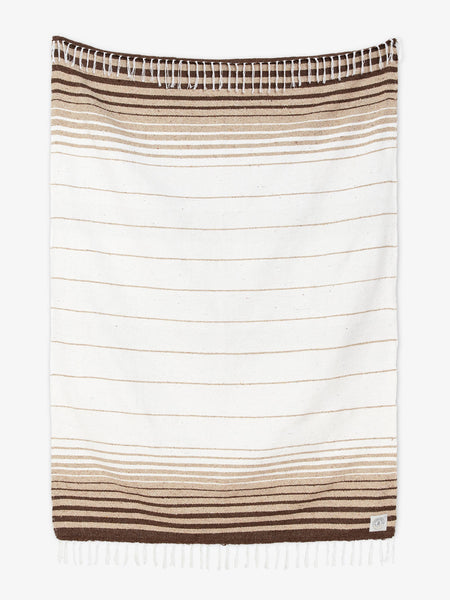 Oversized, traditional Mexican blanket in brown, tan, and white stripe pattern with white fringe spread out.