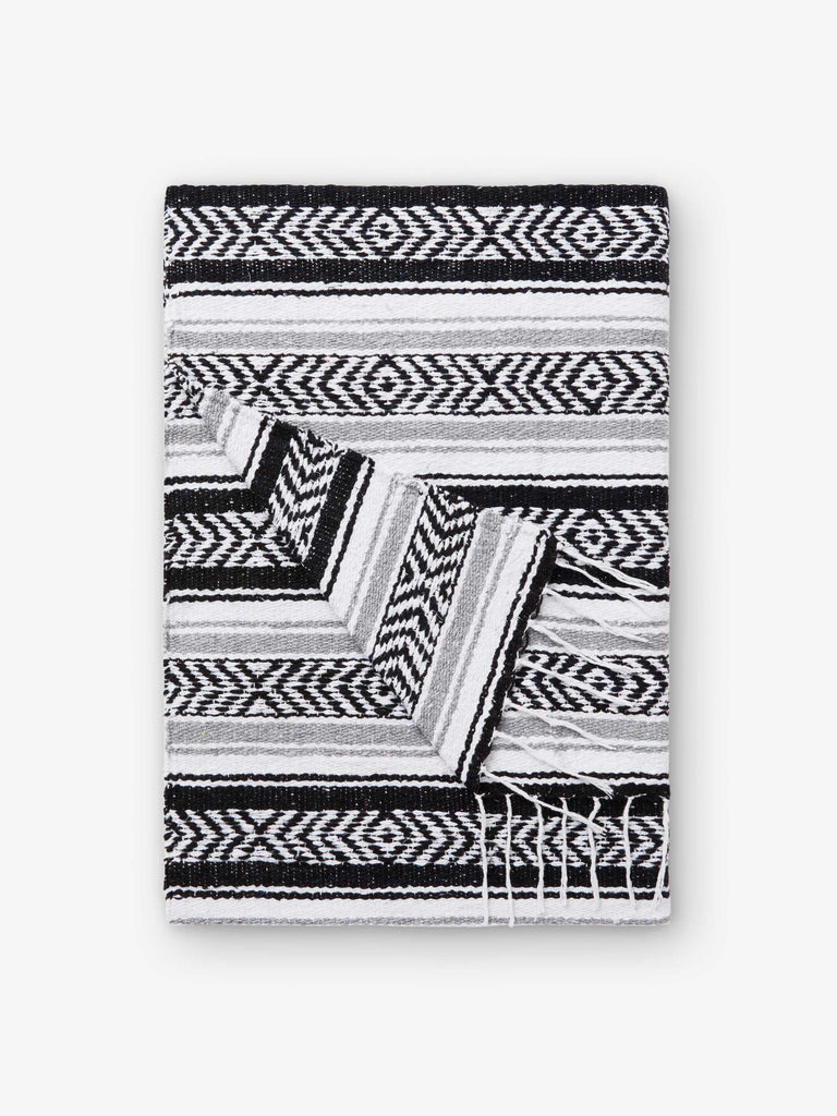 A folded traditional, hand-woven Mexican blanket in black, gray, and white.