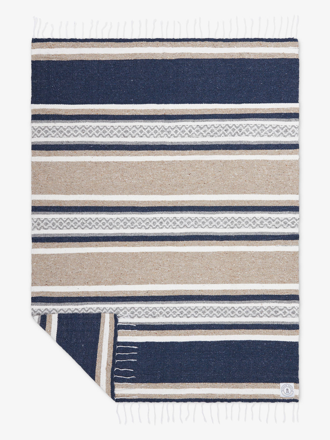 Oversized, traditional Mexican blanket in gray, tan, and white pattern with white fringe spread out.