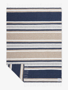 Oversized, traditional Mexican blanket in gray, tan, and white pattern with white fringe spread out.