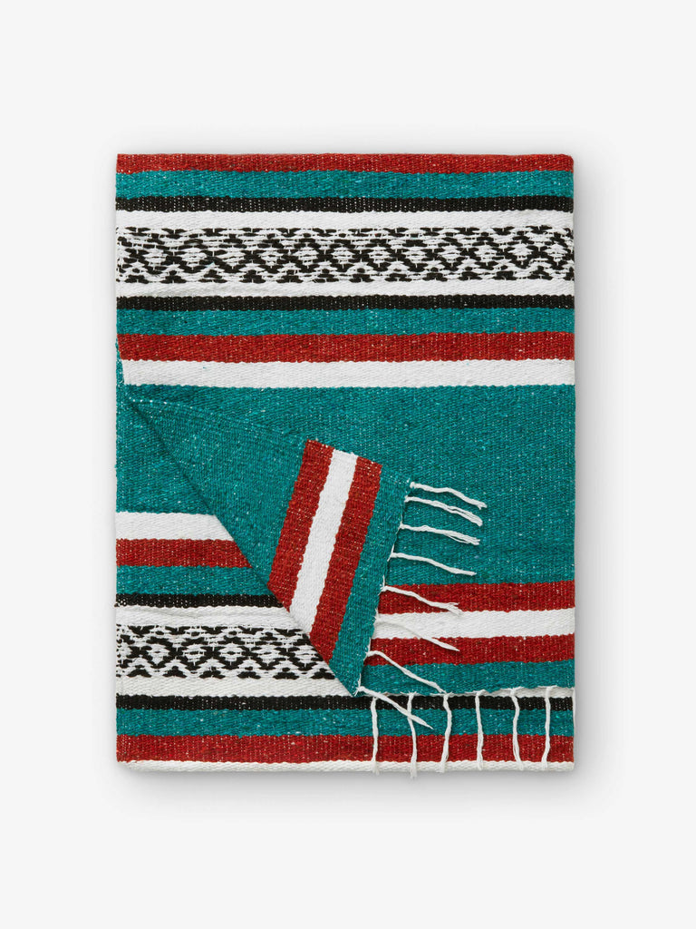 A folded traditional, hand-woven Mexican blanket in green, red, and white pattern with fringe.