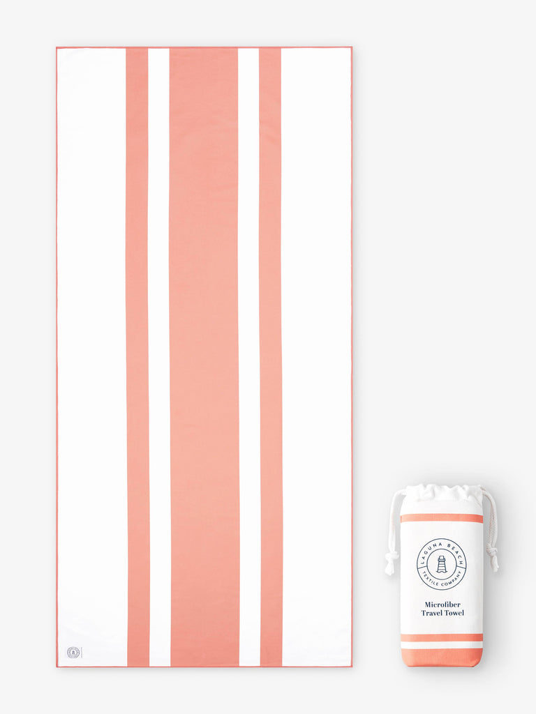 An oversized, quick drying coral and white striped microfiber beach towel laid out next to a matching travel bag.