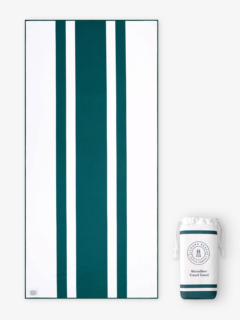 An oversized, quick drying green and white striped microfiber beach towel laid out next to a matching travel bag.