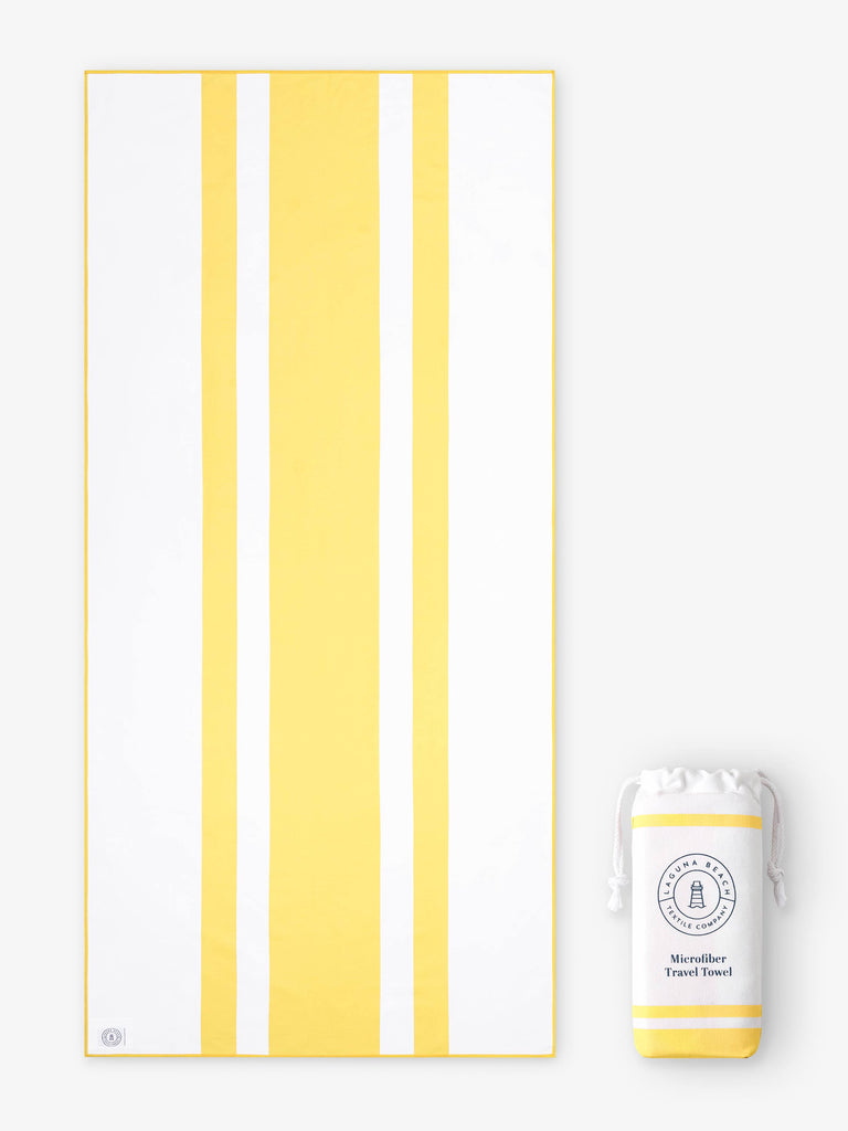 An oversized, quick drying yellow and white striped microfiber beach towel laid out next to a matching travel bag.