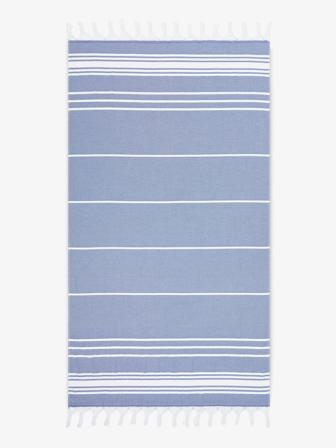 An oversized, blue and white striped Turkish cotton towel with white fringe laid out.