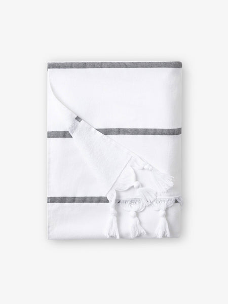 A folded white and gray striped Turkish towel with white fringe.