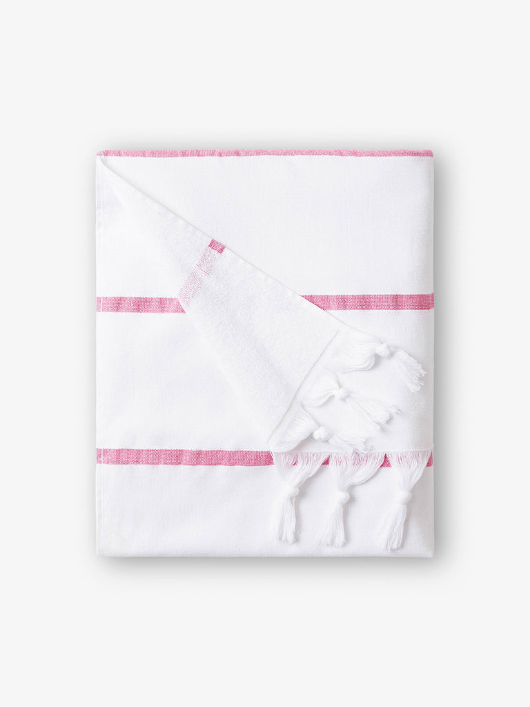 A folded white and pink striped Turkish towel with white fringe.