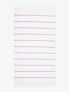 An oversized, white and pink striped Turkish cotton towel with white fringe laid out.