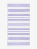 An oversized, white and purple striped Turkish cotton towel with white fringe laid out.