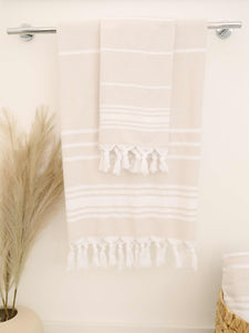 Two tan and white striped hand towels folded and hanging in a restroom.