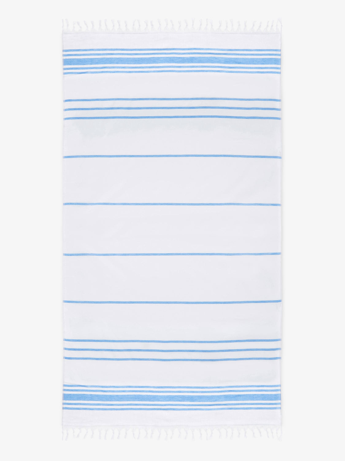 An oversized, white and light blue striped Turkish cotton towel with white fringe laid out.