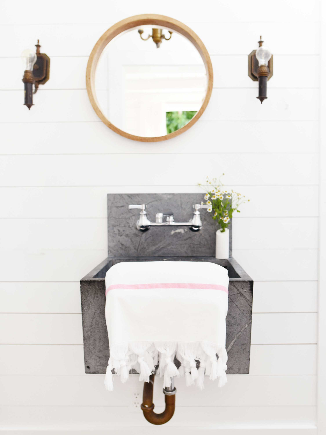 A folded white and pink striped Turkish bath towel hanging over a bathroom sink.