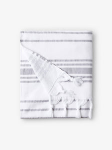 A folded white and gray striped Turkish towel with white fringe.