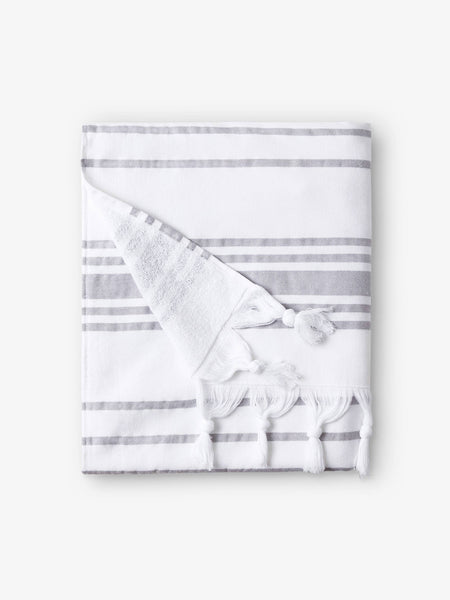 A folded white and gray striped Turkish towel with white fringe.