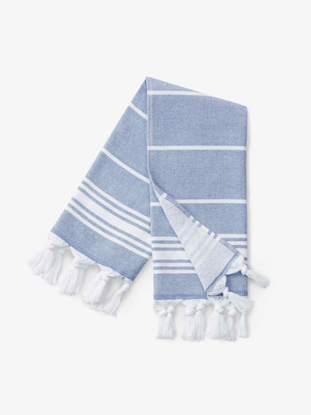 A folded blue and white striped Turkish hand towel with white fringe.