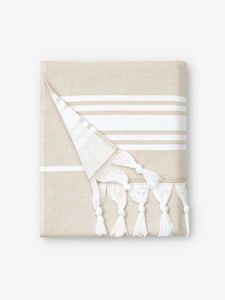 A folded white and tan striped Turkish towel with white fringe.