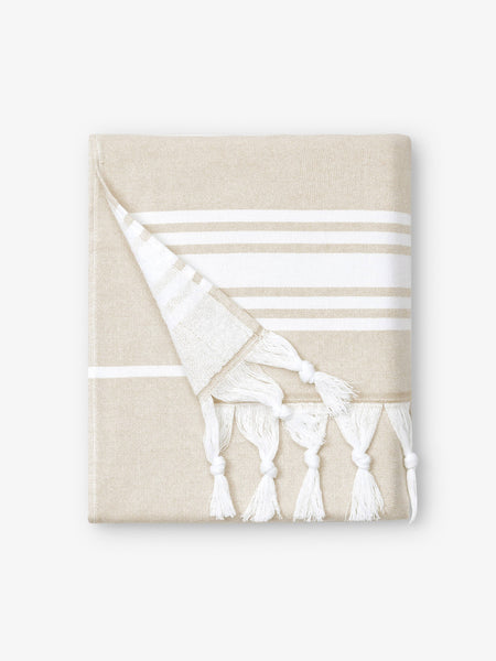 A folded white and tan striped Turkish towel with white fringe.
