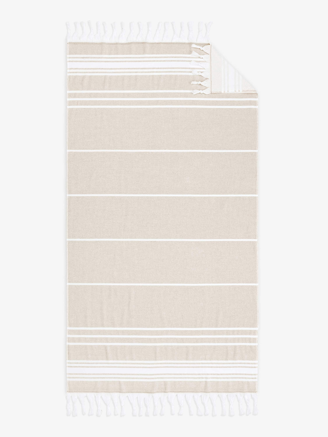 An oversized, tan and white striped Turkish cotton towel with white fringe laid out.