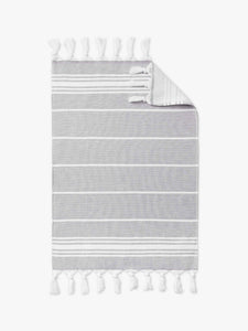 A stone gray and white striped Turkish cotton hand towel with white fringe laid out.