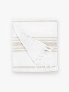 A folded tan and white striped Turkish hand towel with white fringe.