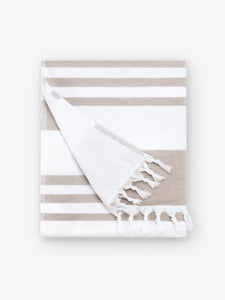 A folded tan and white striped Turkish towel with white fringe.
