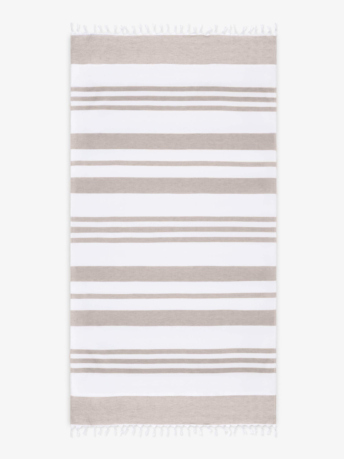 An oversized, tan and white striped Turkish cotton towel with white fringe laid out.