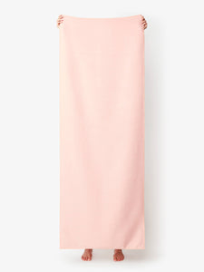 A blush colored yoga mat towel being held up by a person.