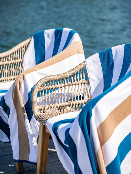 Tan and navy blue soft striped luxury cabana beach towels on a lake. 
