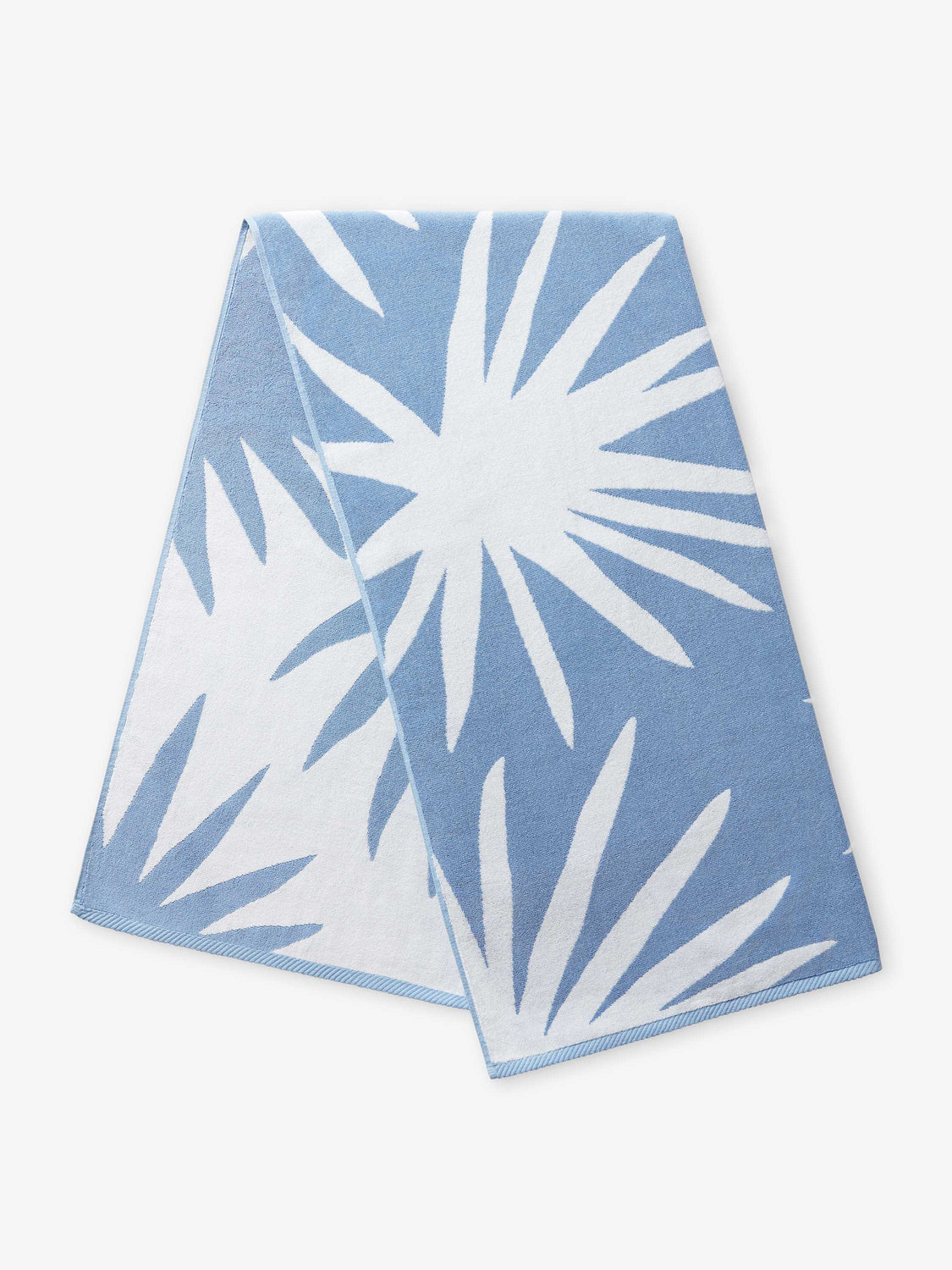 A folded blue and white tropical patterned cabana beach towel.