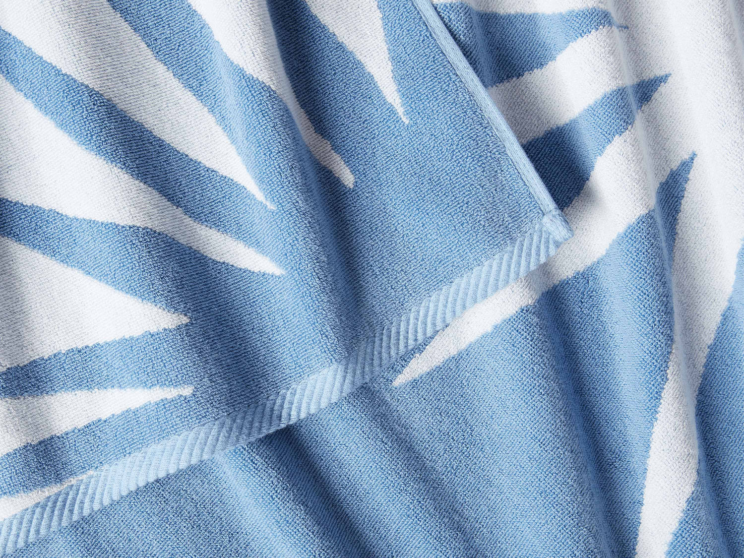
      A close-up of a thick and soft, blue and white tropical patterned cabana beach towel.
    
