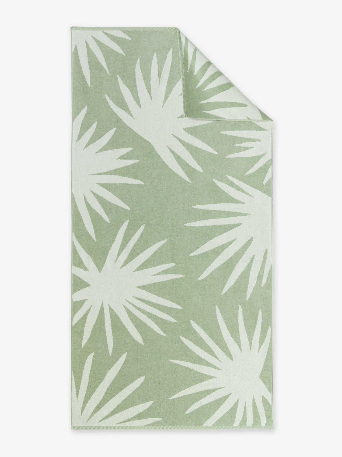 An oversized, green and white palm tree patterned cabana beach towel laid out.