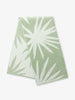 A folded green and white tropical patterned cabana beach towel.
