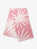 A folded pink and white tropical patterned cabana beach towel.