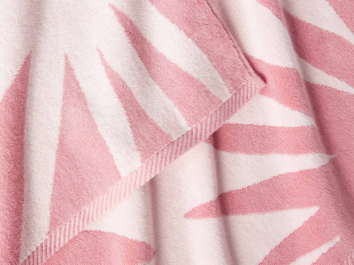 
      A close-up of a thick and soft, pink and white tropical patterned cabana beach towel.
    